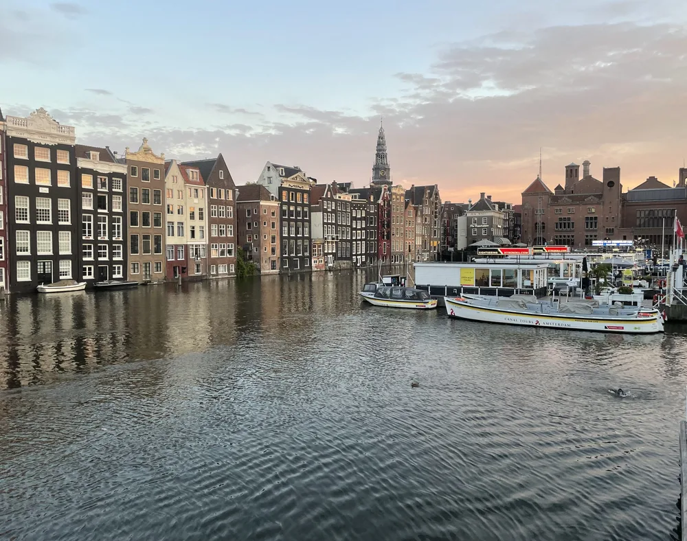 Canal houses and moored boats at dusk in Amsterdam.