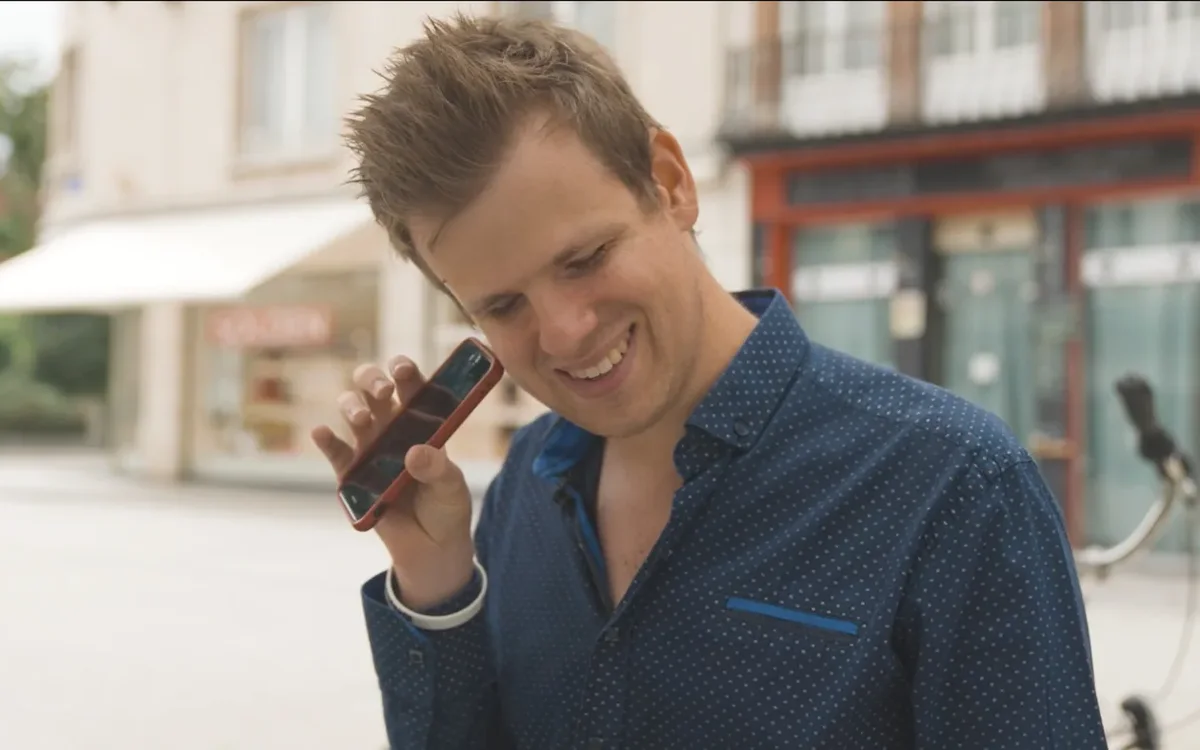 Anthony Reyers smiling, holding a phone to his ear on a city street.
