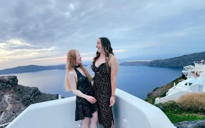 Marybai Huking and Eliana Mason standing together above the caldera in Santorini at dusk.