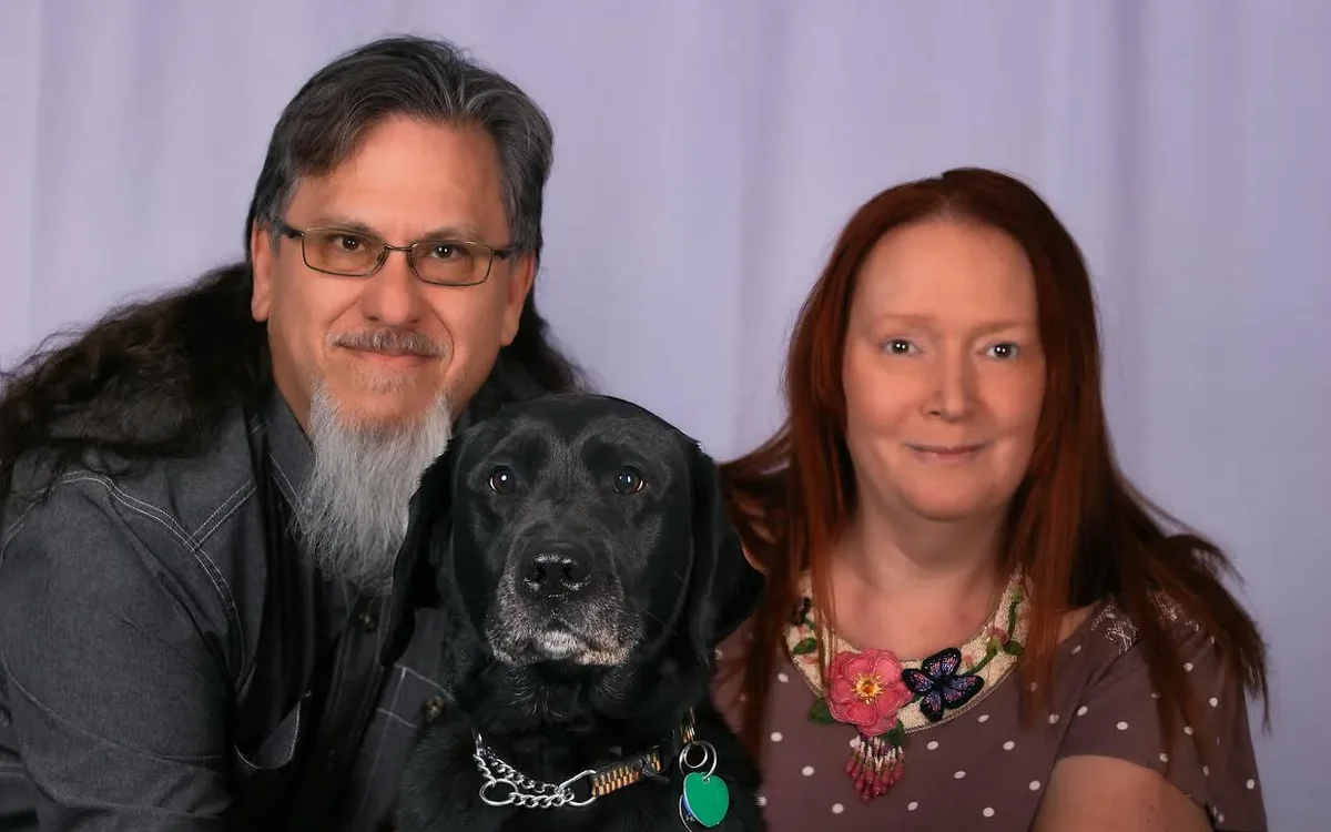 Ted and Carrie Tahquechi with their black guide dog Fauna sitting between them.