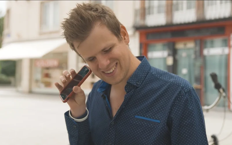 Anthony listening to his phone, wearing a blue shirt.
