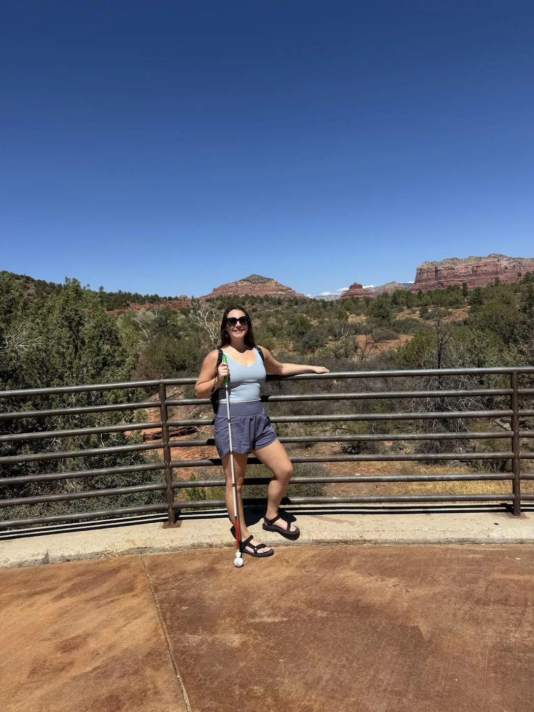 A photo of Monica at the visitor center with some trees and rocks behind her.