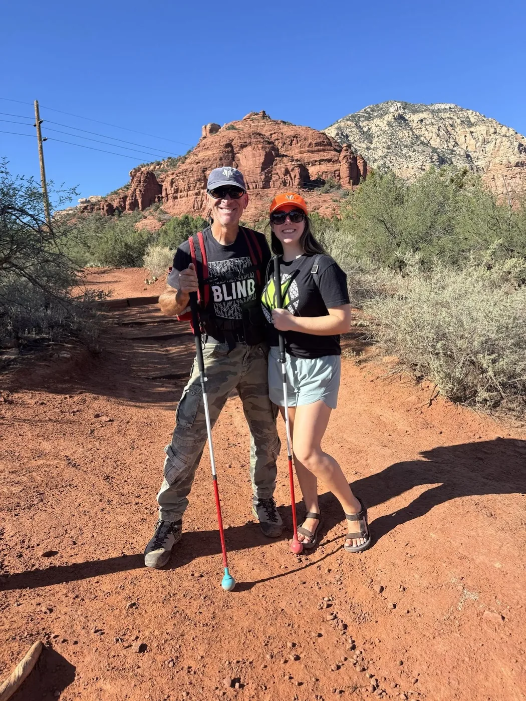 A photo of Dave and Monica posing for a picture in front of a rock in Sedona.