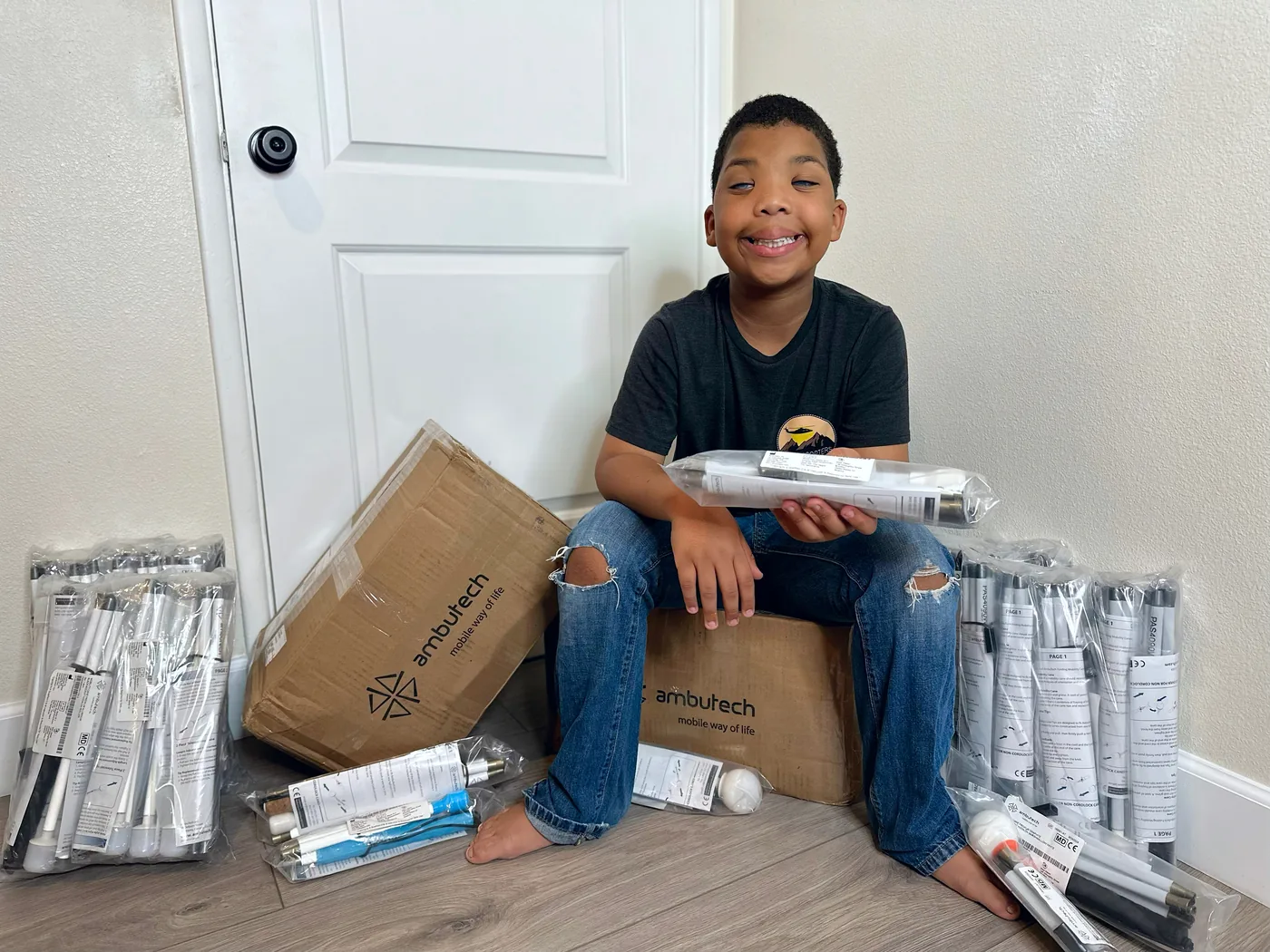 Grayson Roberts is sitting and showing the white canes from Ambutech he is taking to Ghana.