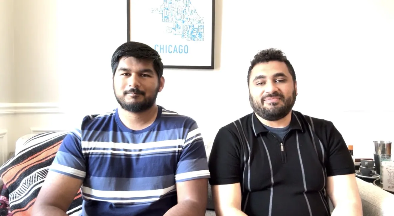 Khaleel and Muhammad sitting side by side on a sofa in front of a framed Chicago print.