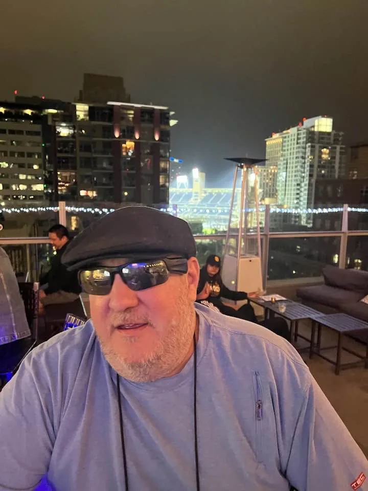 Brian on a rooftop at night with Petco Park in the background.