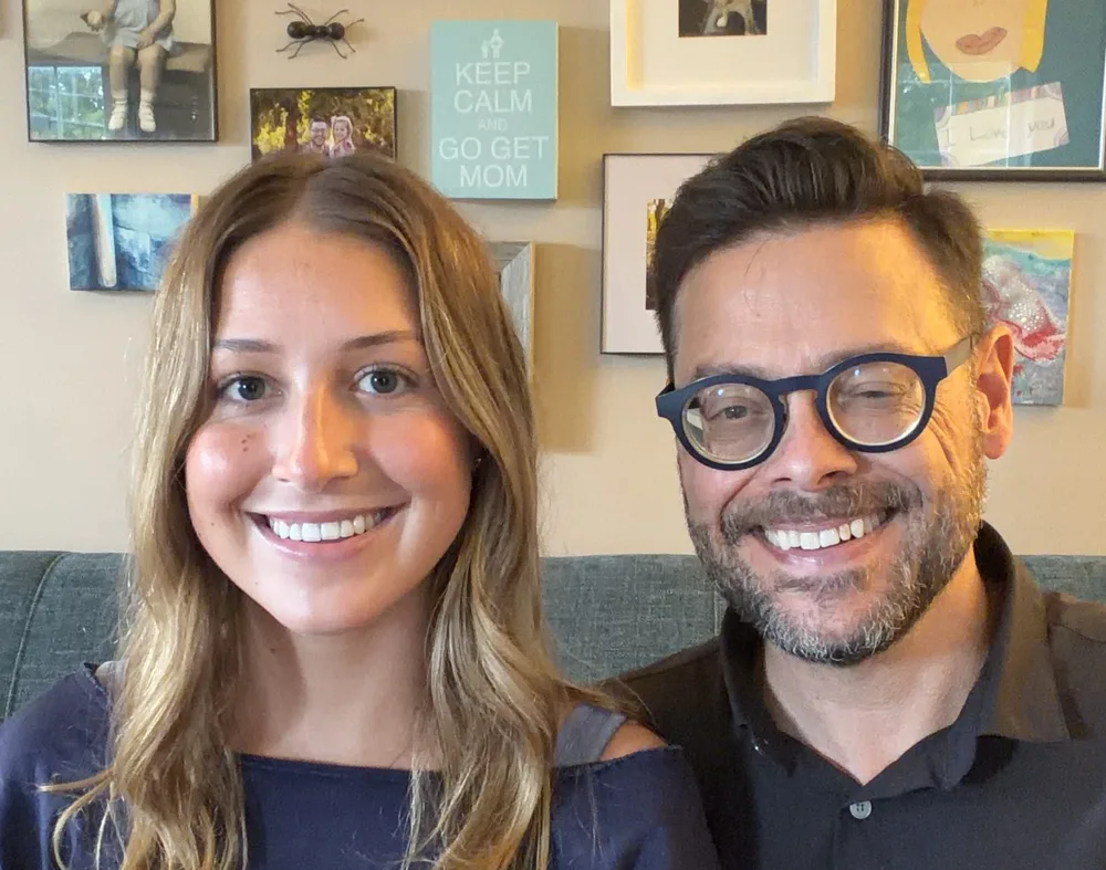 Josh and Eileen Loebner, side by side, smiling in a room hung with framed pictures.