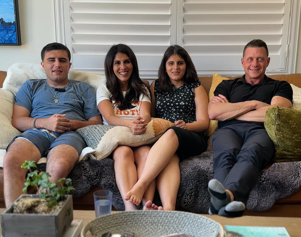 A family of four seated together on a sofa.